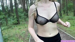 Mulher loira se exercita ao ar livre no parque, expondo seu corpo nu e seios saltitantes
